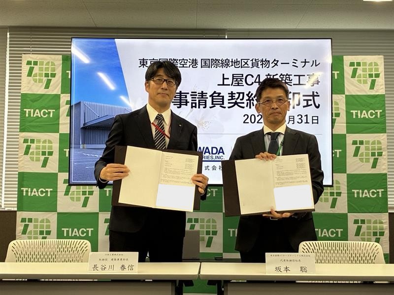 契約書を掲げる建築事業部長　長谷川（左）と坂本社長（右）